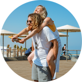 Blond girl sitting on man’s back at a beach